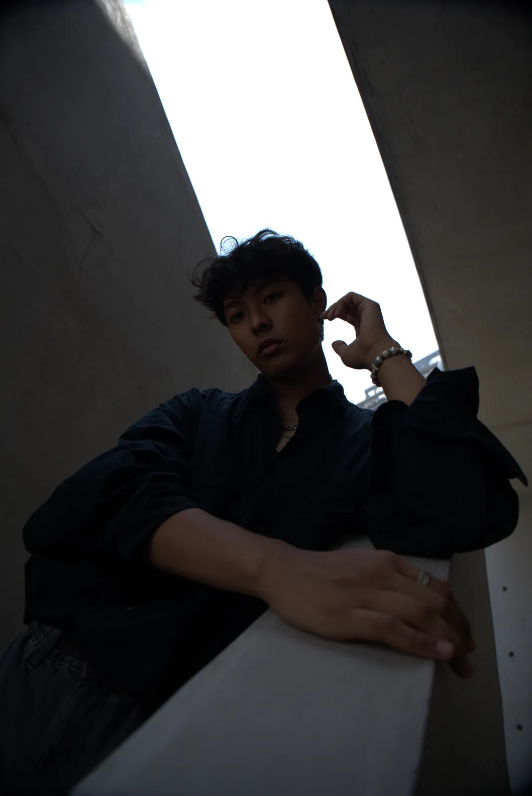 Julius in a dark shirt leaning over a concrete stairwell railing.