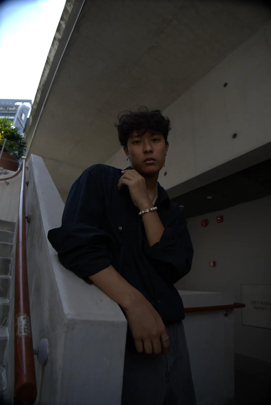 Julius facing the camera from a concrete stairwell, with one hand beside his face.