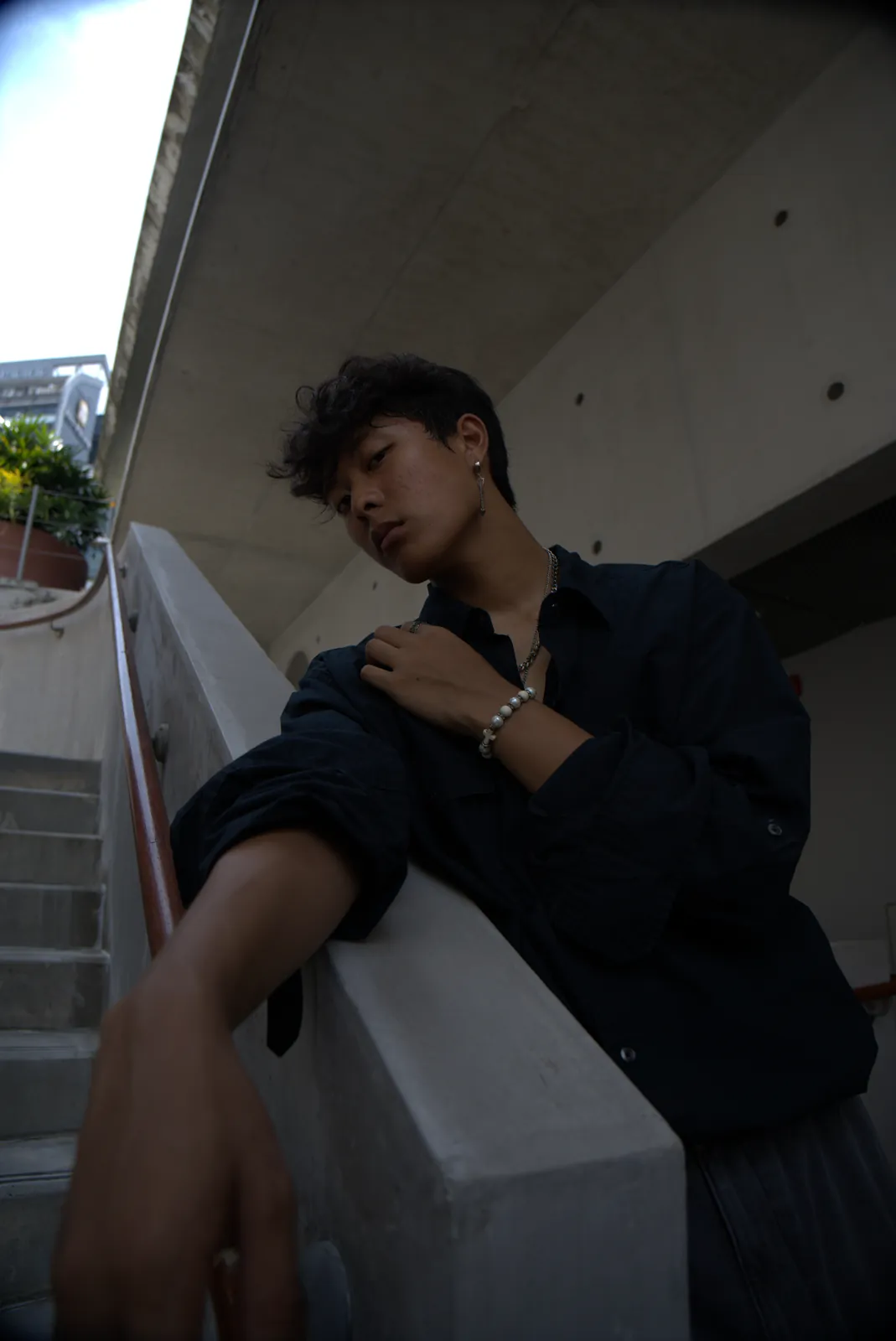 Julius looking to the side while leaning against a concrete stairwell railing.