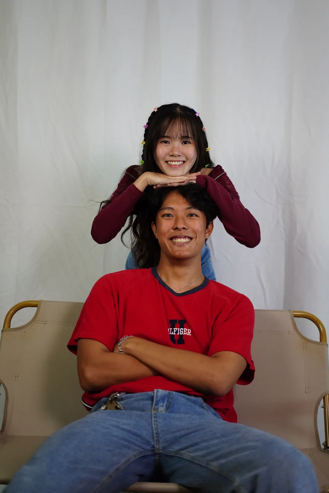 Julius laughing in a red shirt as another model rests her hands on his head.